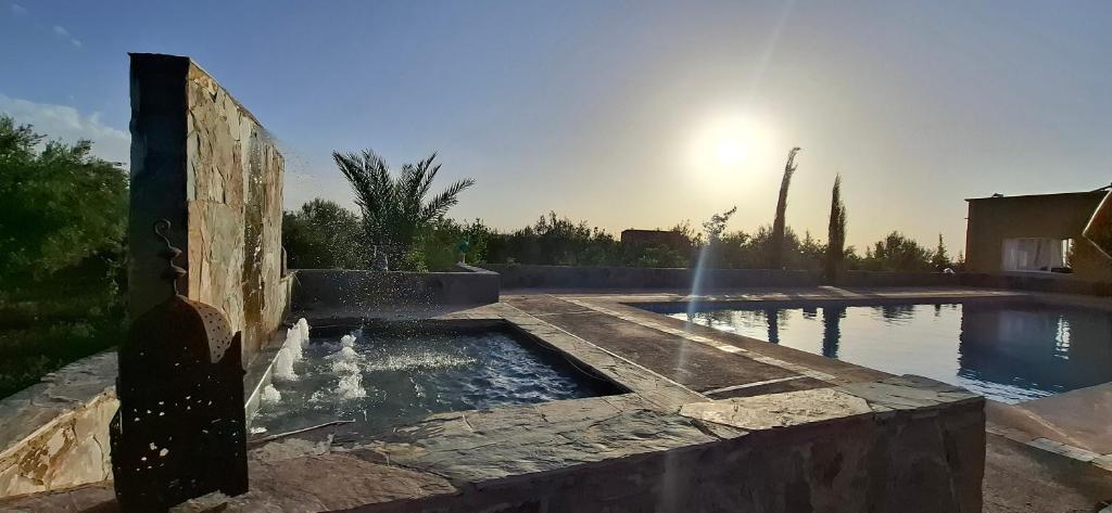 Fontaine et bassin de pierre au bord de la piscine au coucher du soleil